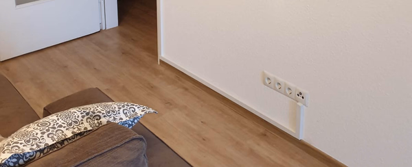 Renoviertes Wohnzimmer mit neu installierten Steckdosen und elegantem Kabelkanal entlang der Wand